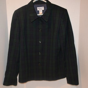 Op de afbeelding: Een zwart-groen gestreept blazer met een knoopsluiting en een kraag. Het label op de blazer luidt "Pinakoteka".