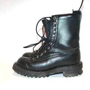 May include: A pair of black leather work boots with a lace-up design. The boots have a rugged, textured sole and metal eyelets. The boots are approximately 8 inches tall.