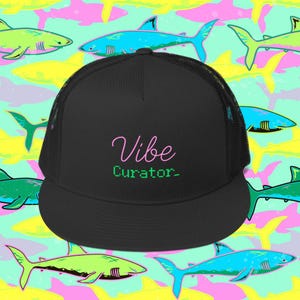 Könnte beinhalten: Schwarze Trucker-Mütze mit Mesh-Rückseite und gebogenem Schirm. Auf der Mütze steht der Text "Vibe Curator-" in Pink und Grün. Der Hintergrund ist ein sich wiederholendes Muster aus Haien in verschiedenen Farben, darunter Blau, Grün und Gelb.
