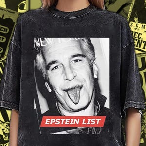 Puede incluir: Una camiseta negra con efecto lavado al ácido que presenta una impresión fotográfica en blanco y negro de un hombre sacando la lengua. Debajo de la imagen, un gráfico rectangular rojo contiene el texto blanco "EPSTEIN LIST" en mayúsculas.