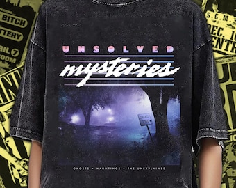 Puede incluir: Una camiseta negra con efecto lavado al ácido que presenta un estampado gráfico con el texto UNSOLVED mysteries. El diseño muestra un bosque oscuro y neblinoso de noche con un pequeño cartel que dice DEAD END y el texto GHOSTS - HAUNTINGS - THE UNEXPLAINED.