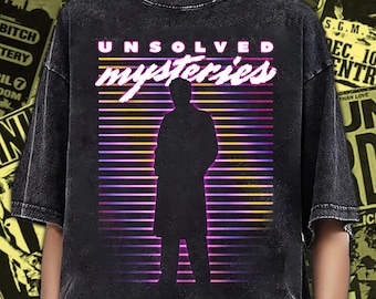 Puede incluir: Una camiseta negra con efecto lavado al ácido que presenta un estampado gráfico con el texto "UNSOLVED mysteries" en blanco y rosa. El diseño incluye la silueta de una persona sobre un fondo de líneas horizontales en degradado morado, rosa y naranja.