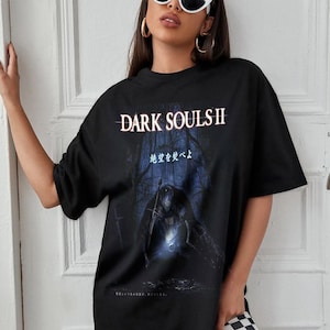 May include: Black graphic t-shirt featuring the text "DARK SOULS II" in white, with a dark forest scene and a figure holding a sword. The shirt has Japanese text below the graphic.