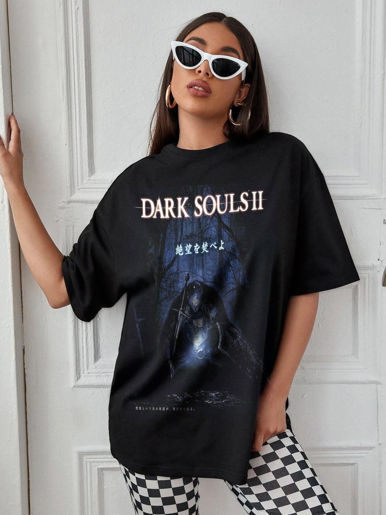 May include: Black graphic t-shirt featuring the text "DARK SOULS II" in white, with a dark forest scene and a figure holding a sword. The shirt has Japanese text below the graphic.