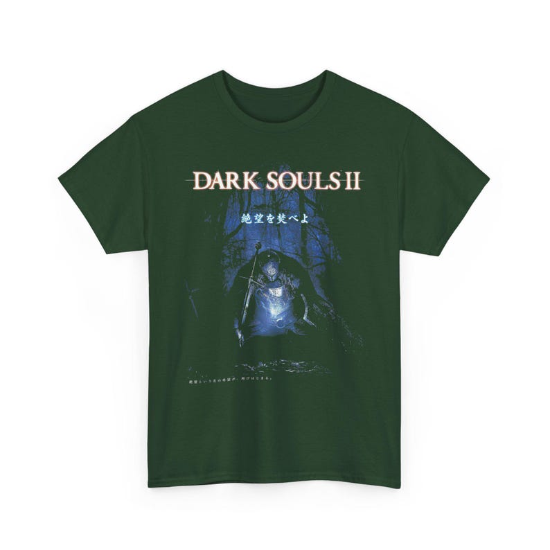 May include: Dark green t-shirt featuring the text "DARK SOULS II" above a blue and black graphic of a figure with a sword in a forest setting. Japanese text is also present.