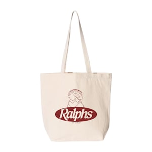 May include: A cream-coloured tote bag featuring a cartoon illustration of a child and the word "Ralphs" in a maroon oval. The bag has long handles. The text "TV Kaiju" is below the word "Ralphs".