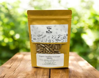 May include: A brown paper bag with a clear window displaying brown capsules. The bag has a white label with the text "Vita Herbs" and "Organic Japanese Knotweed 1000mg". The background is a blurred green foliage.