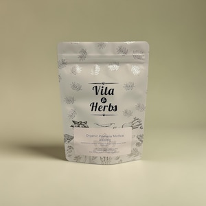 Può includere: Un sacchetto bianco con un motivo a foglie argentate e la scritta "Vita & Herbs". Il sacchetto contiene "Organic Pueraria Mirifica 1000mg". Il design include illustrazioni di erbe e spezie. Il sacchetto è sigillato e si erge in posizione verticale.