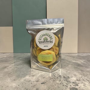 May include: A clear, metallic bag filled with dried pawpaw slices. The bag has a circular label with the text "Vita & Herbs" and "Organic". A smaller label reads "Dried Pawpaw Slices". The background is a mix of green, beige, and gray.