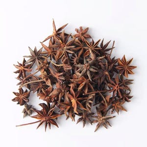May include: A pile of star anise spices, featuring a rich brown color and star-shaped pods. The spices are arranged on a white background, showcasing their unique shape and texture. These aromatic spices are commonly used in cooking and baking.