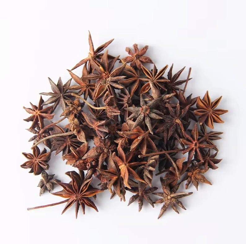 May include: A pile of star anise spices, featuring a rich brown color and star-shaped pods. The spices are arranged on a white background, showcasing their unique shape and texture. These aromatic spices are commonly used in cooking and baking.