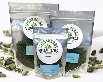 May include: Three silver resealable pouches of organic tea. The pouches are labeled with a green circle logo that says "Vita & Herbs". The smallest pouch is labeled "Mulberry Tea". The middle pouch is labeled "Mulberry Tea". The largest pouch is labeled "Elderberry Tea".