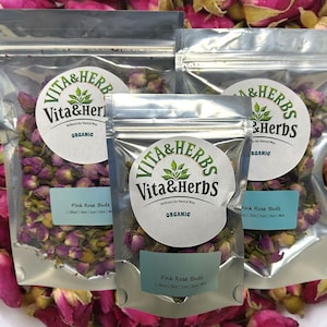 Może przedstawiać: Trzy srebrne saszetki z różowymi pąkami róż. Saszetki są oznaczone "Vita & Herbs" i "Organic".