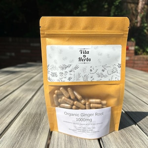 May include: A tan-colored stand-up pouch containing brown capsules. The label features the text Vita & Herbs, Organic Ginger Root, 1000mg, and a botanical illustration. The pouch has a clear window showing the capsules inside the packaging.