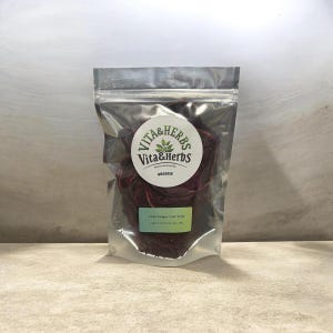 May include: A clear, resealable bag containing dried dragon fruit slices. The bag features a white circular label with "Vita & Herbs" and "Organic". A green label at the bottom reads "Dried Dragon Fruit Slices".