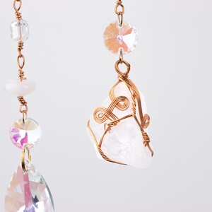 May include: A white crystal wrapped in copper wire hangs from a chain with iridescent glass beads. The crystal is a rough, natural shape and the wire is twisted into a decorative design.