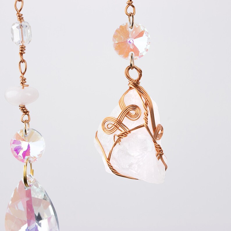 May include: A white crystal wrapped in copper wire hangs from a chain with iridescent glass beads. The crystal is a rough, natural shape and the wire is twisted into a decorative design.