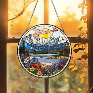 May include: A circular stained glass window suspended by a chain. It depicts a mountain scene with a lake, trees, and vibrant flowers. The sky is a blend of yellow, orange, and blue hues.
