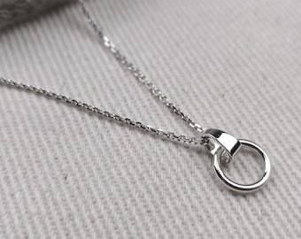 May include: A silver chain necklace with a small, simple circle pendant.