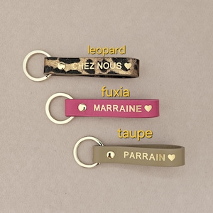 May include: Three leather keychains with gold lettering and a heart symbol. The keychains are in leopard print, fuchsia, and taupe.