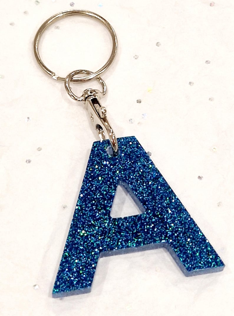 May include: A blue glitter letter A keychain with a silver key ring and clasp.