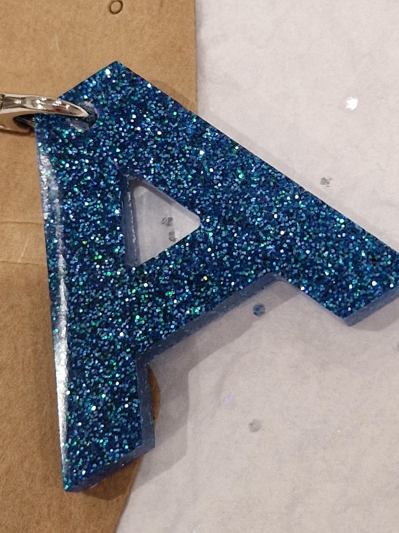 May include: A blue glitter resin keychain shaped like the letter A.