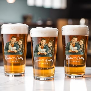 May include: Three clear pint glasses filled with beer and foam. Each glass features a personalized image of a man and a girl holding a sign that says "FOR DAD". The glasses are inscribed with "Sophia Daddy" and the date 12.06.2024.