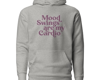 May include: A heather gray hooded sweatshirt featuring the dark purple text Mood Swings are my Cardio printed on the chest. The garment includes a front kangaroo pocket, long sleeves with ribbed cuffs, and a drawstring hood with metal eyelets.