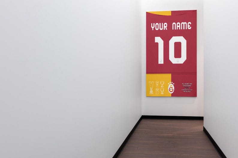 May include: A red and yellow poster with the text "YOUR NAME" and the number "10" in white. The poster is hanging on a white wall.