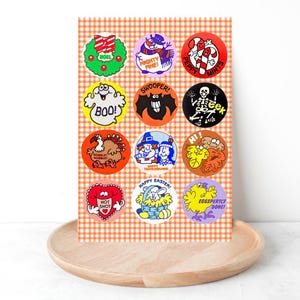 Puede incluir: Una hoja de pegatinas de vacaciones de estilo vintage con varios diseños. Las pegatinas incluyen imágenes de una corona navideña, un muñeco de nieve, bastones de caramelo, un fantasma, un murciélago, un esqueleto, un pavo, peregrinos, hojas de otoño, un corazón, una cesta de Pascua y un pollito.