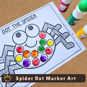 May include: A white activity sheet with the text DOT THE SPIDER featuring a black outline of a spider with large eyes and legs. The spider's body contains circles filled with red, orange, yellow, green, and purple ink dots. Three dot markers are nearby.