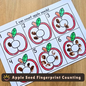 May include: A white educational worksheet titled I can count apple seeds! featuring six outlined red apples with green leaves. Each apple is numbered one through six and contains brown fingerprint marks representing seeds inside the fruit shapes.