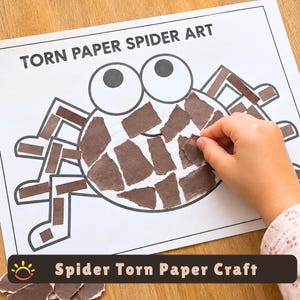 May include: A white paper sheet with the black printed text TORN PAPER SPIDER ART and a spider outline. The spider body and legs are partially filled with small, irregular brown paper pieces. A hand is placing a brown paper piece on the spider.