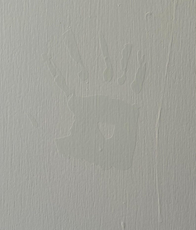 May include: A white handprint on a light gray textured surface.