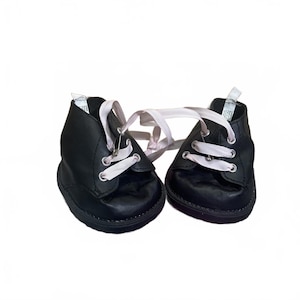 May include: A pair of black leather baby shoes with white laces. The shoes have a classic design with a rounded toe and a low ankle. The laces are tied together.