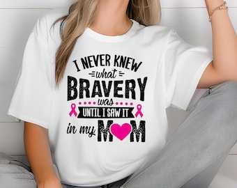 May include: White t-shirt with a black graphic that reads "I never knew what bravery was until I saw it in my mom". The graphic also includes two pink ribbons and a pink heart.