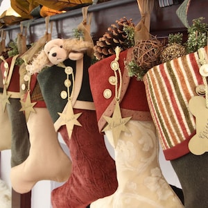 Seven coordinating yet unique Christmas stockings are hanging from a stocking rod on a mantel. Each stocking has a star name tag hanging from the top of three buttons on each stocking's cuff.