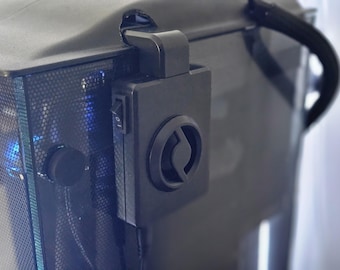 May include: A black computer case with a fan mounted on the side. The fan has a black circular grill with a silver logo in the center. The case has a black power switch on the side.