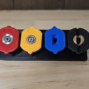 May include: Four different colored nozzle tips for a pressure washer. The tips are red, yellow, blue, and black. The tips are mounted on a black plastic holder.