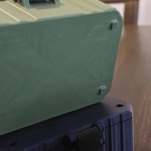 K&ouml;nnte beinhalten: Drei gr&uuml;ne, blaue und beige rechteckige Aufbewahrungsboxen sind auf einer Holzoberfl&auml;che gestapelt. Die Boxen haben einen Griff oben und kleine quadratische F&uuml;&szlig;e unten. Die Boxen haben ein geripptes Design an den Seiten.