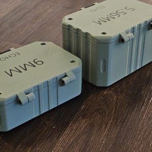 K&ouml;nnte beinhalten: Zwei graue Aufbewahrungsboxen mit Klappdeckeln. Eine ist mit "9MM" und die andere mit "5.56MM" beschriftet. Beide haben das Wort "ECHO" aufgedruckt. Die Beh&auml;lter sind rechteckig und scheinen aus Kunststoff zu sein.