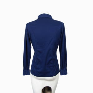 May include: A navy blue long-sleeve shirt with a button-down collar. The shirt has a tailored fit with seams running down the back. The cuffs have button closures. The shirt is displayed on a white mannequin.