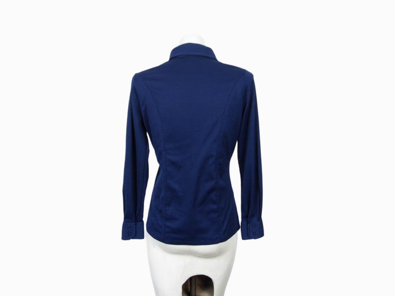 May include: A navy blue long-sleeve shirt with a button-down collar. The shirt has a tailored fit with seams running down the back. The cuffs have button closures. The shirt is displayed on a white mannequin.
