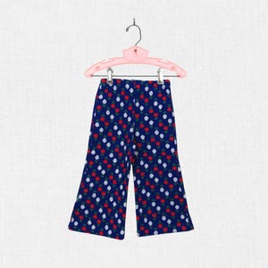 May include: Navy blue pants with a repeating pattern of red and white flowers. The pants are hanging on a pink hanger. The pants have a wide leg design.