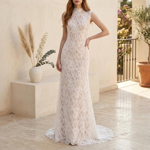 May include: A white lace gown with a high neckline and sleeveless design. The dress is floor-length, with a fitted bodice and a slight flare towards the hem, complete with a small train. The intricate lace detailing covers the entire dress, creating an elegant look.