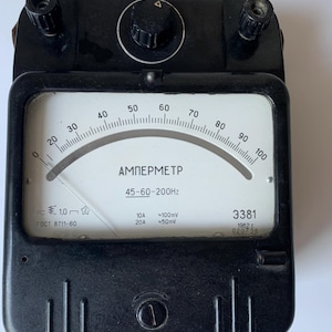 May include: A black vintage ammeter with a white face and a curved scale from 0 to 100. The gauge reads "AMПEPMETP" and includes text indicating voltage and frequency. The device has two terminals and a central dial.
