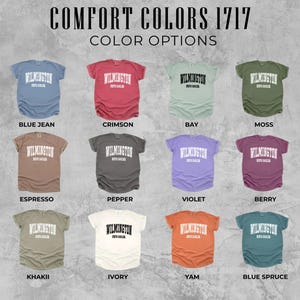 May include: An image showcasing a variety of Comfort Colors 1717 t-shirts in different colors. Each shirt displays the word "Wilmington" in white block letters. Color options include Blue Jean, Crimson, Bay, Moss, Espresso, Pepper, Violet, Berry, Khaki, Ivory, Yam, and Blue Spruce.