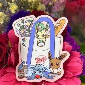 May include: A pink Trader Joe's reusable shopping bag with a blue handle. The bag is filled with a bouquet of flowers, a loaf of bread, and three Pokemon characters: Eevee, Espeon, and Umbreon.