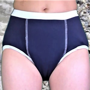 May include: Black swim briefs with white trim. The briefs have a high waist and are made of a smooth, stretchy fabric.