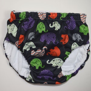 May include: Black swim diaper with a white fleece lining and a colorful elephant print. The print features green, orange, purple, and white elephants on a black background.